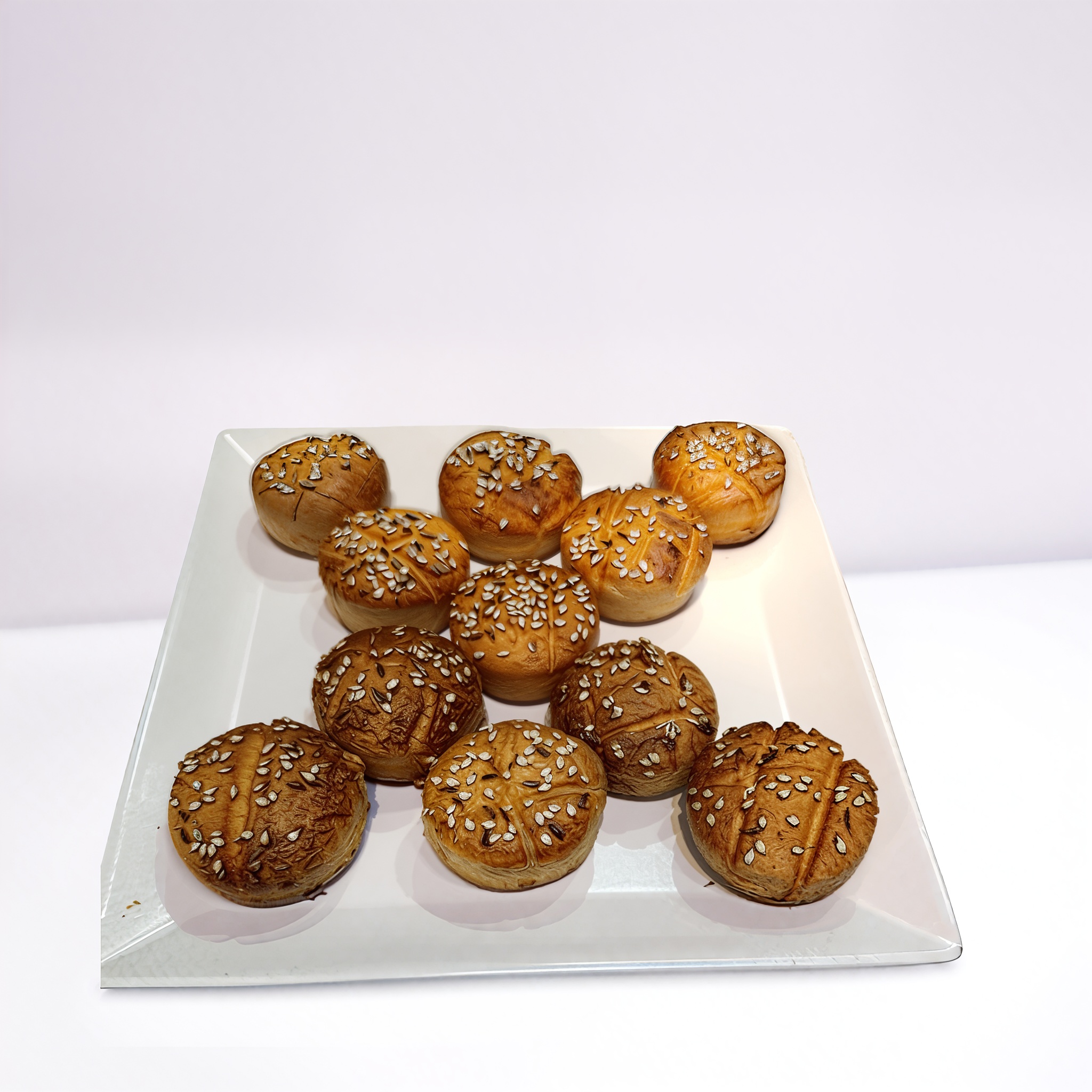 Szezámmagos pogácsák fehér tányéron, háttérben fehér fal.